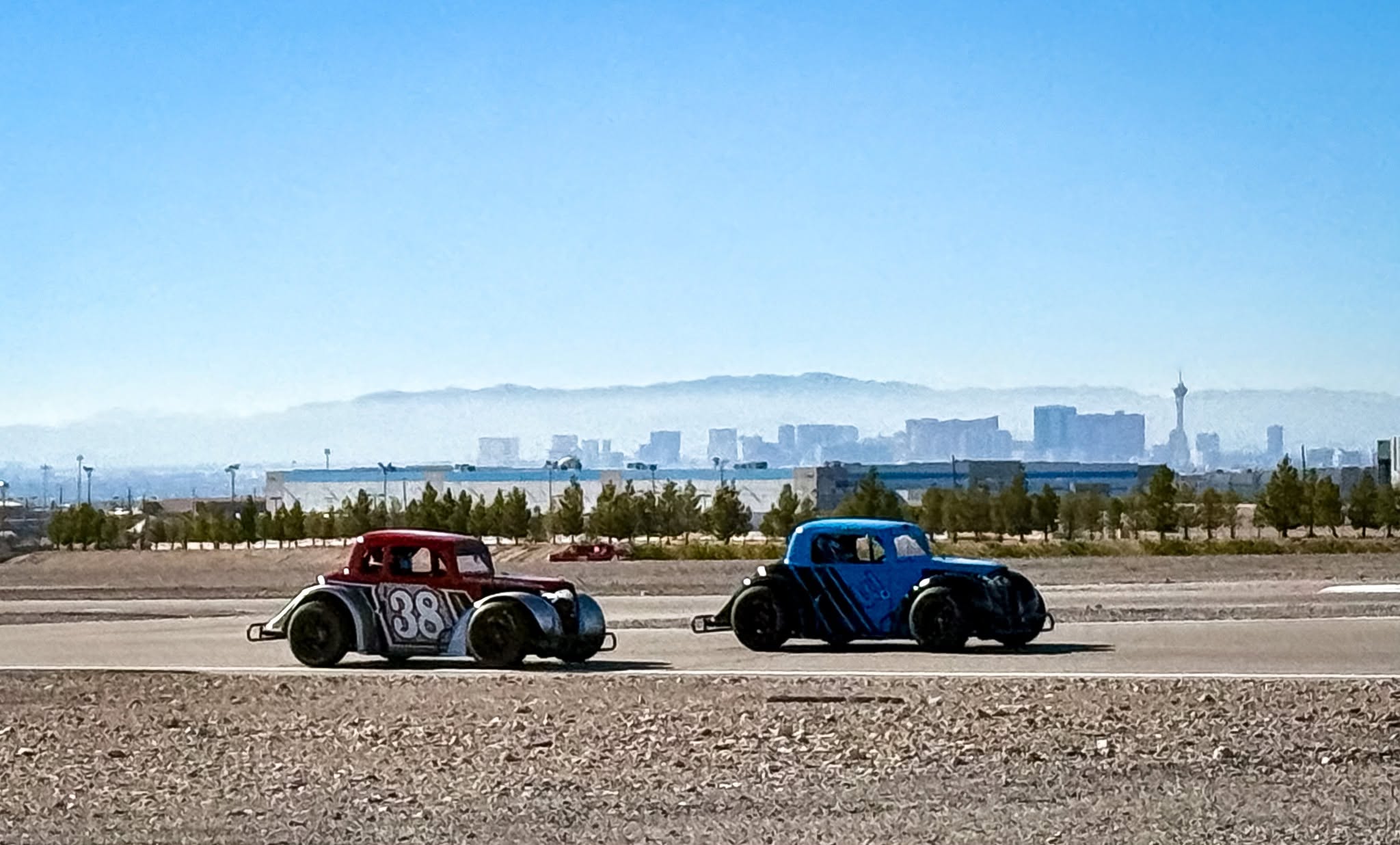 Two Legends race cars running with the Las Vegas skyline in the distance